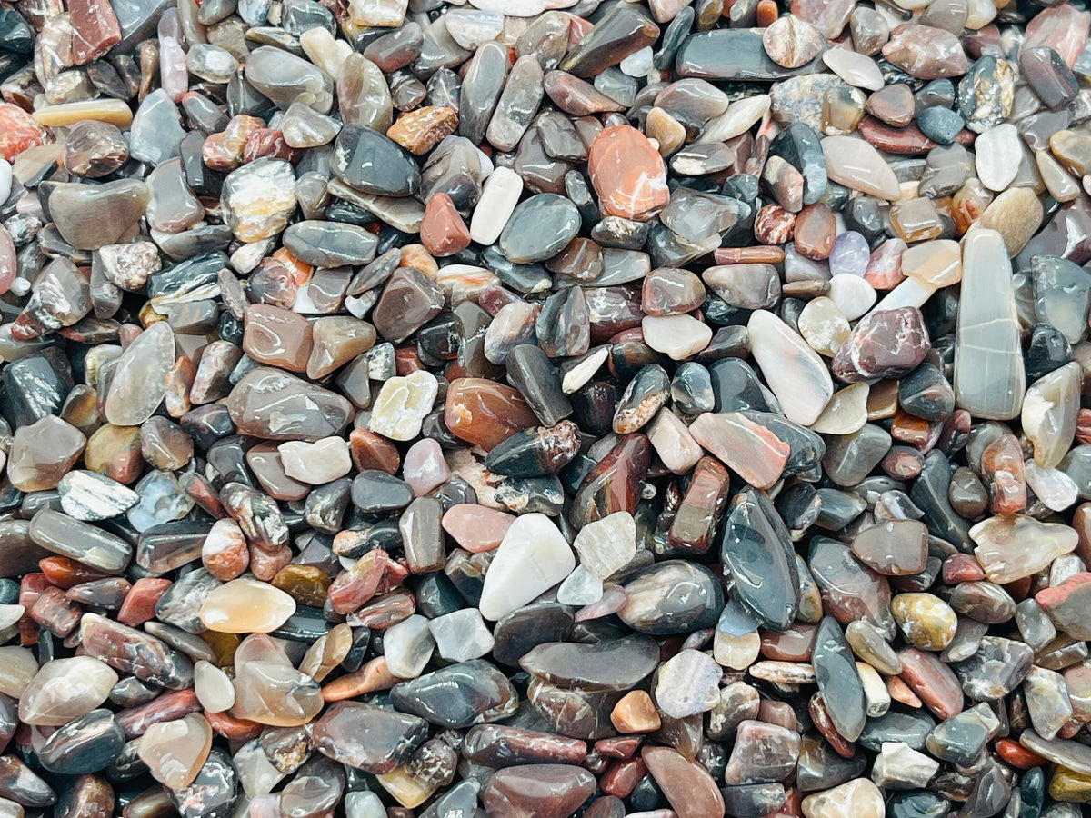 Close-up of semi-tumbled petrified wood crystal chips in 5-7mm size, showcasing natural wood grain patterns and earthy tones.