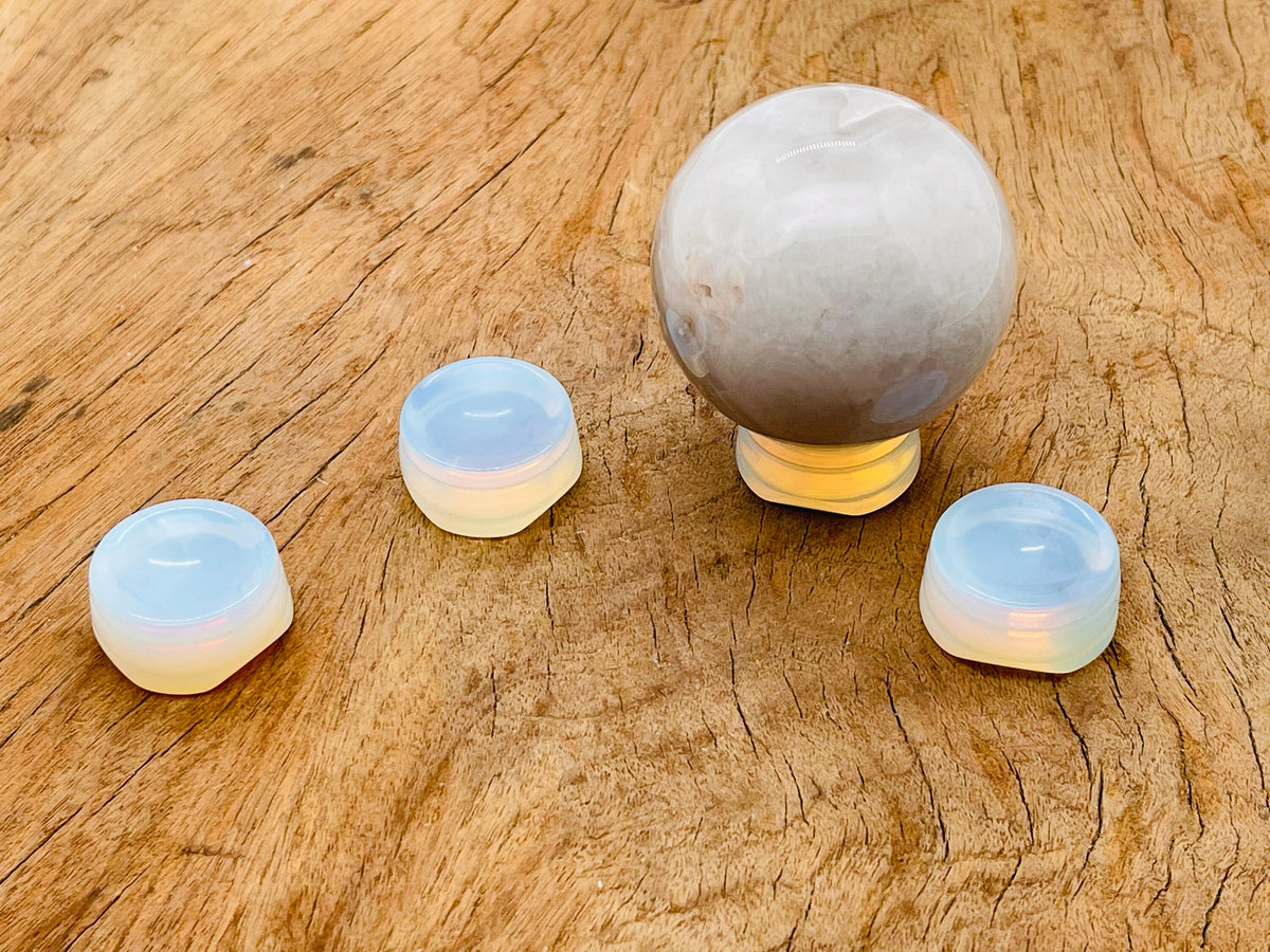 Opalite crystal sphere resting on a carved gemstone stand, used as elegant home decor accent.
