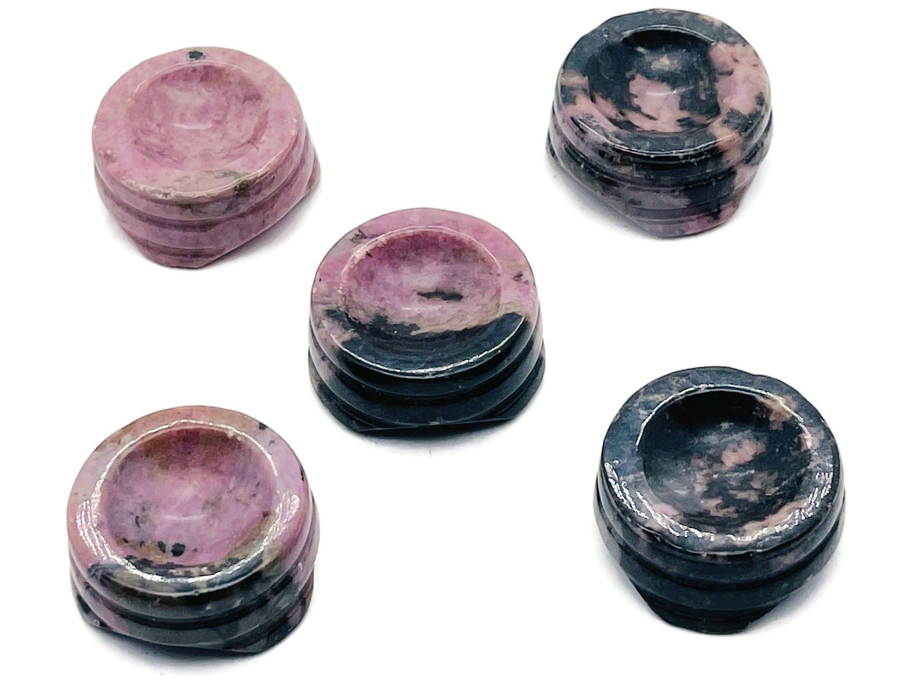 Rhodonite crystal sphere on carved gemstone stand, decorative home decor piece showcasing vibrant pink and black hues.