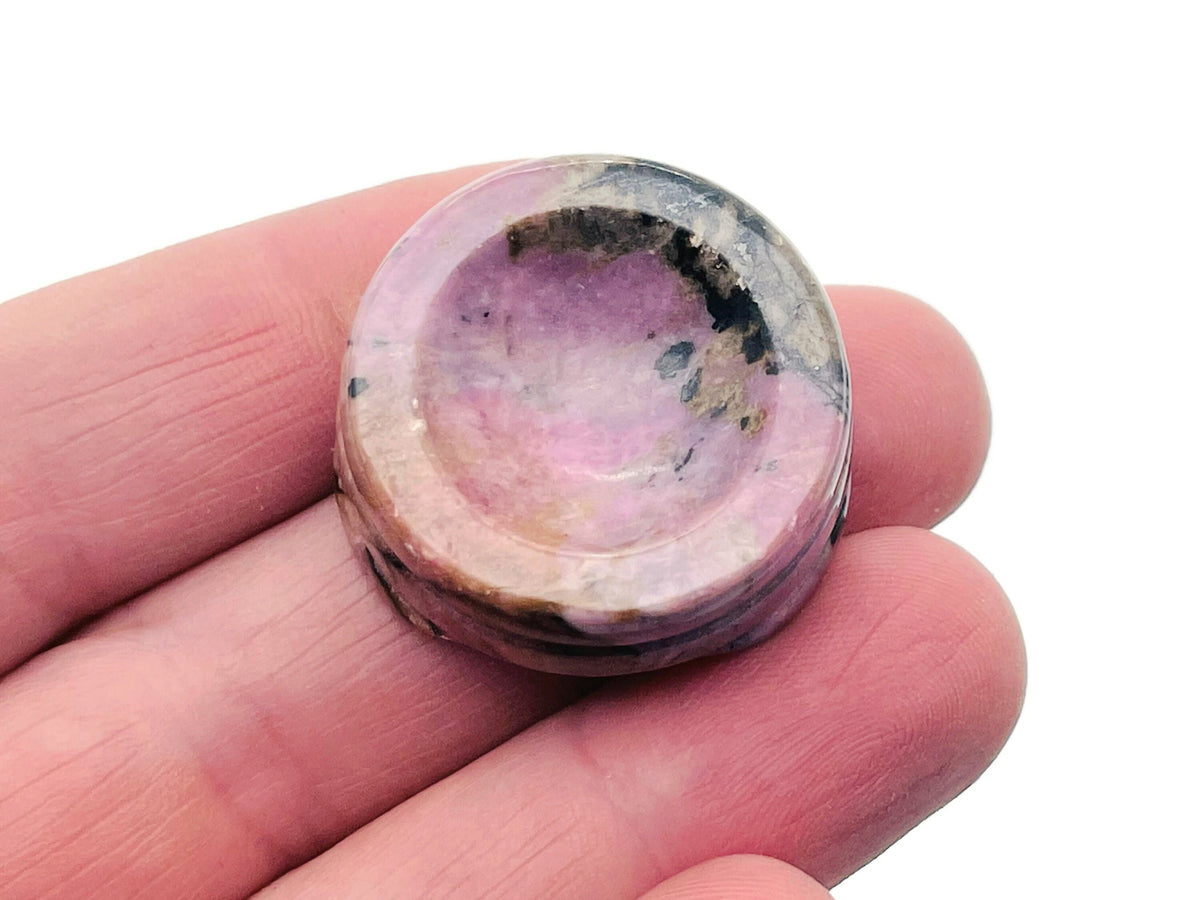 Rhodonite crystal sphere on carved gemstone stand, decorative home decor piece showcasing vibrant pink and black stone details.