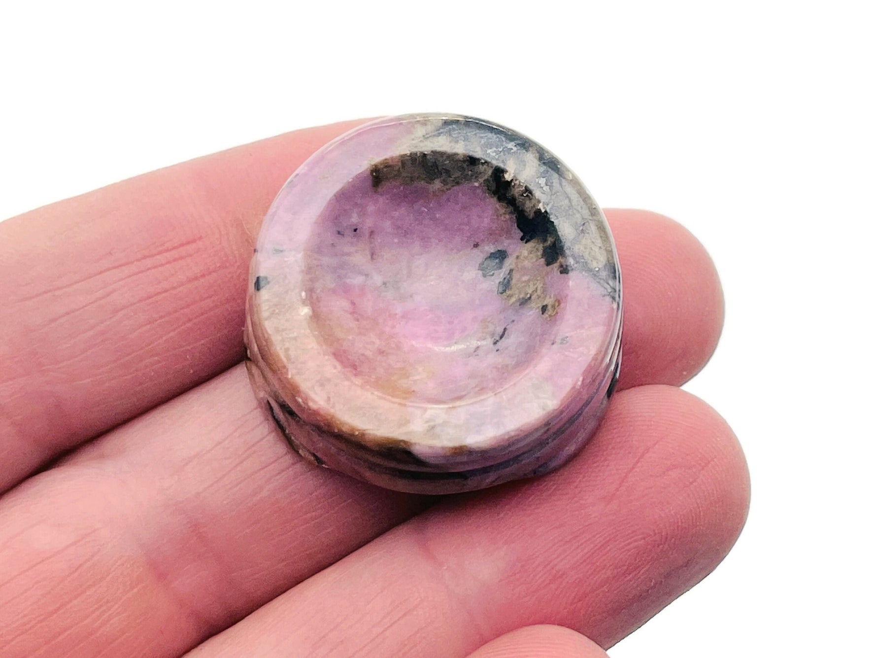 Rhodonite crystal sphere on carved gemstone stand, decorative home decor piece showcasing vibrant pink and black stone details.