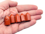 Red Jasper obelisk tower crystal from GemstoneGO, 25mm, showing a smooth, polished red stone with natural patterns and a pointed top.