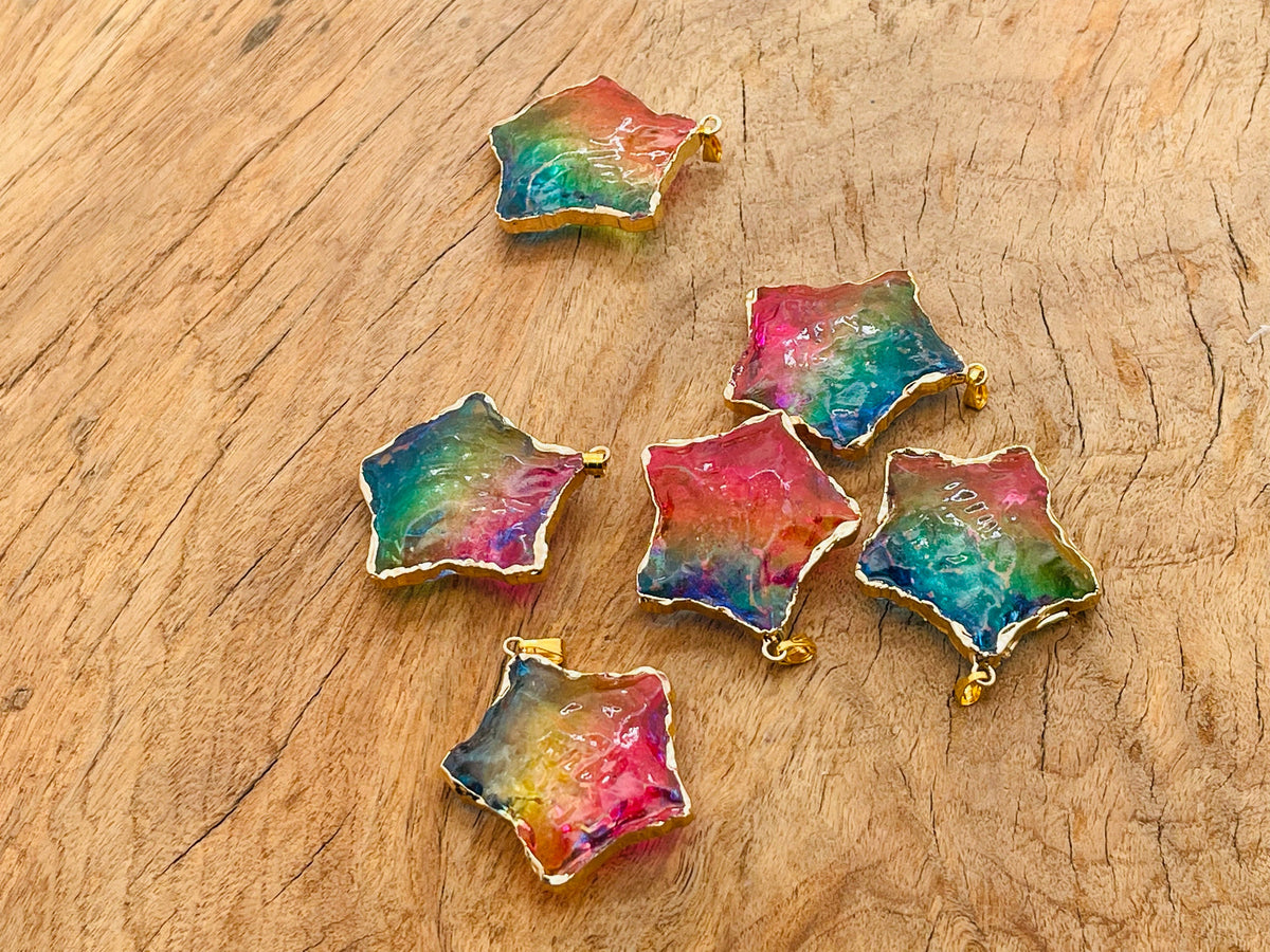 Pink, yellow, and blue rainbow aura star crystal pendant from GemstoneGO, featuring a loose, shimmering star-shaped gemstone.