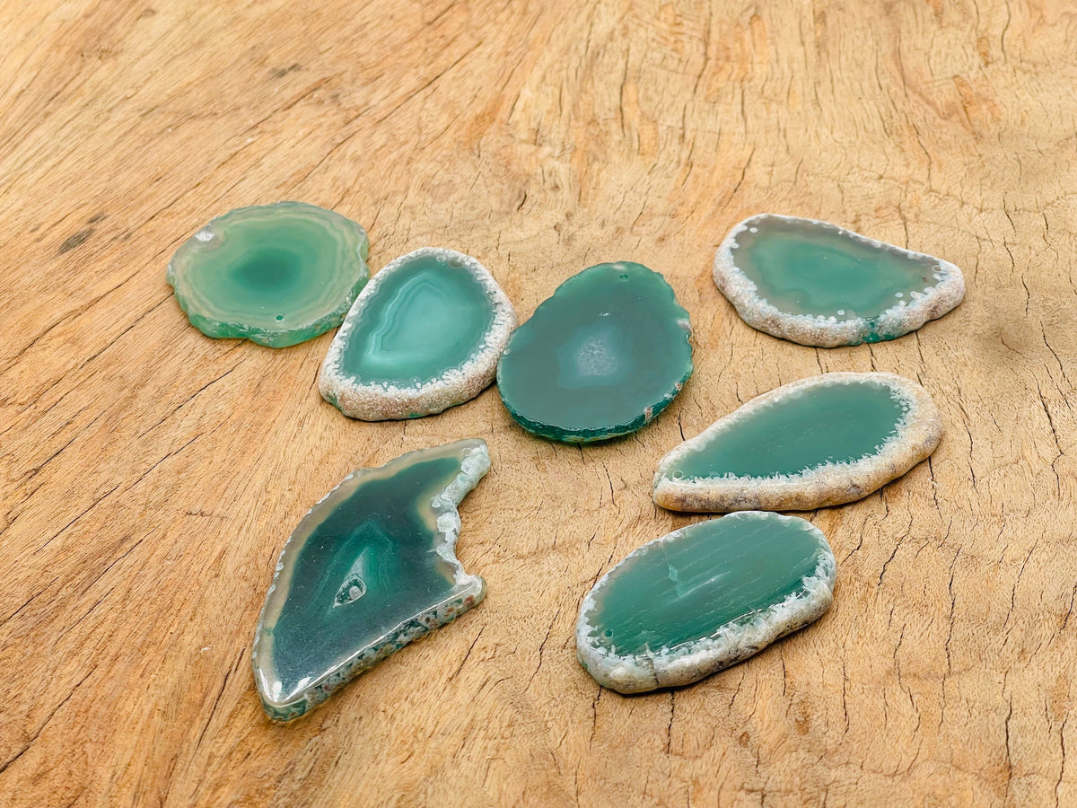 Green agate slice drilled for jewelry making, featuring a natural geode crystal pendant with vibrant green hues and unique stone patterns.