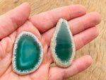 Green agate slice drilled for jewelry making, showcasing a natural geode crystal pendant with vibrant green tones.