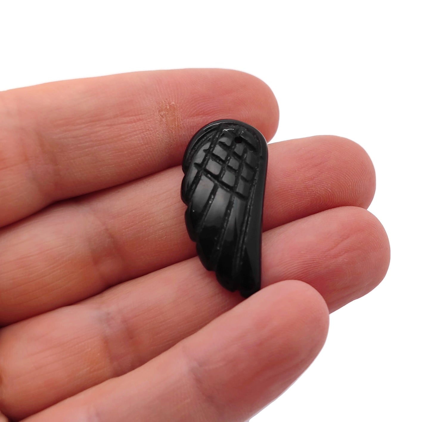 Obsidian angel wing crystal pendant from GemstoneGO showing a detailed black stone angel wing charm with hole for necklace attachment.