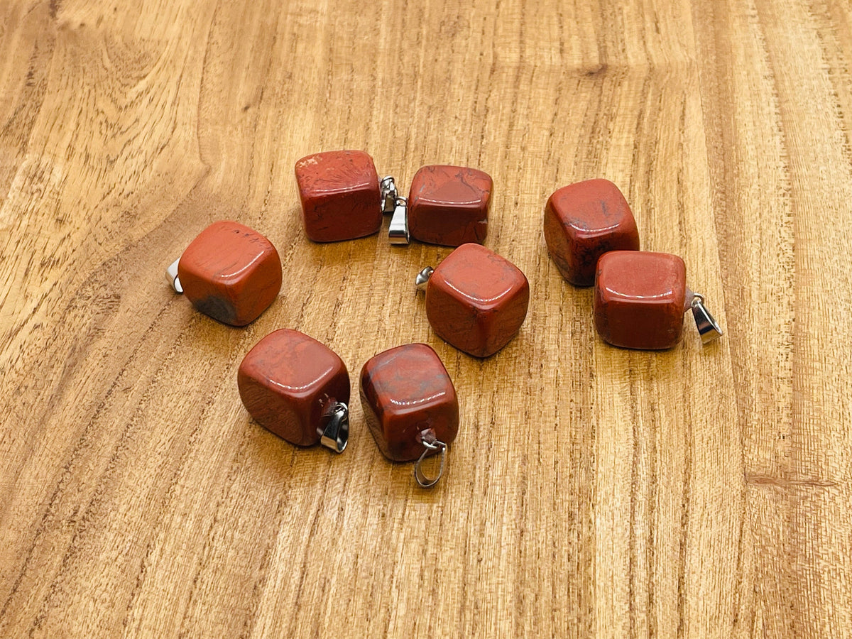 Red Jasper tumbled crystal pendant with silver bail from GemstoneGO, showcasing a smooth, polished red stone on a plain background.