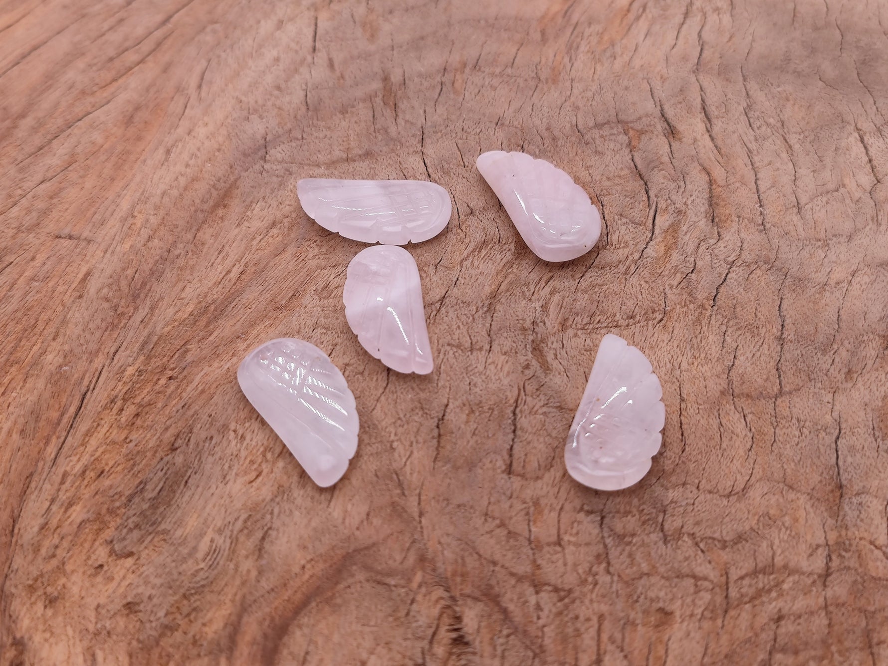 Rose quartz crystal angel wing pendant with carved angel wing design, featuring gemstone jewelry and charm details.