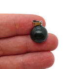 Moss agate crystal ball pendant hanging from a silver chain, showcasing the round gemstone for jewelry making or display.