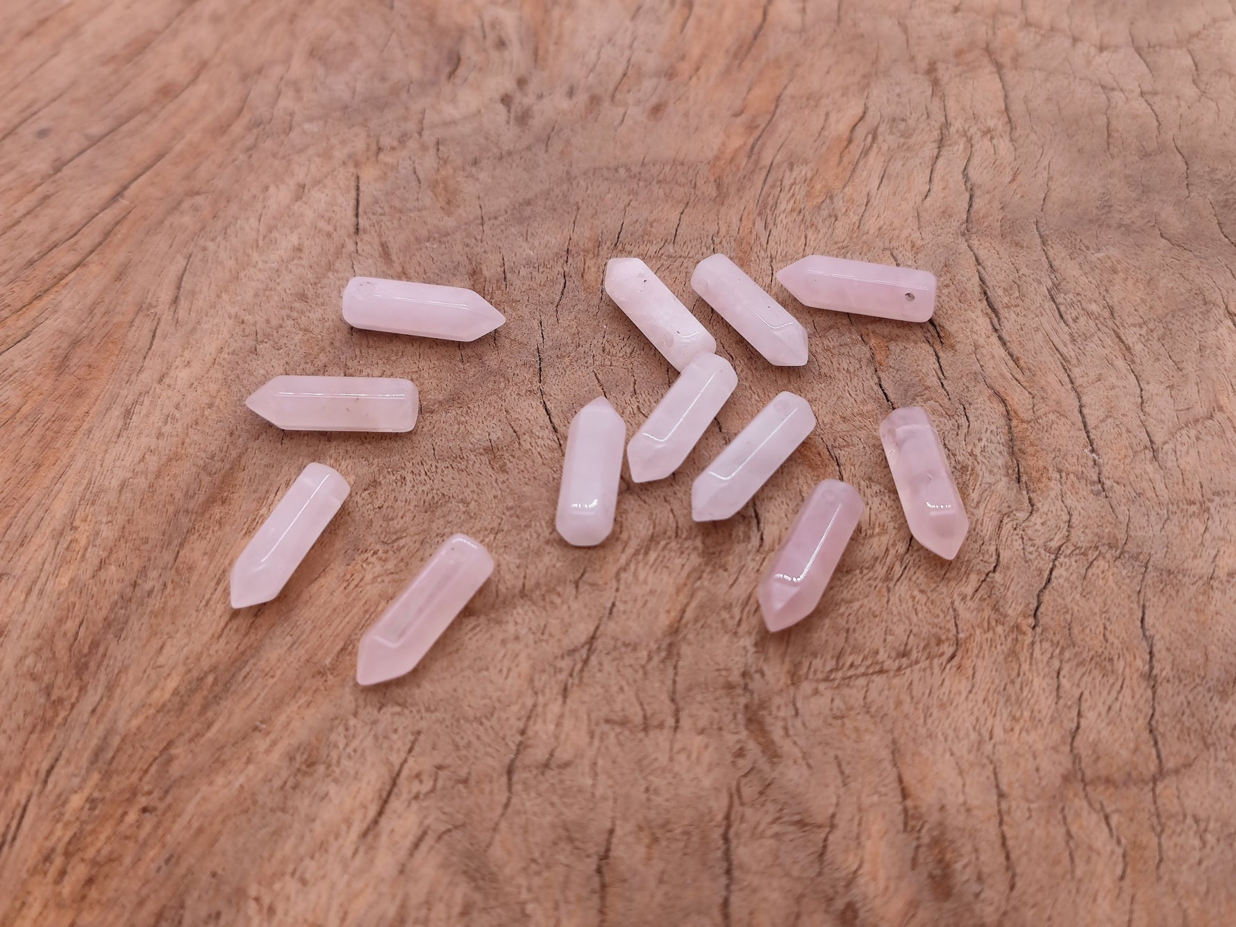 Rose quartz crystal point pendant with drilled hole from GemstoneGO, showcasing a polished pink gemstone with natural facets.