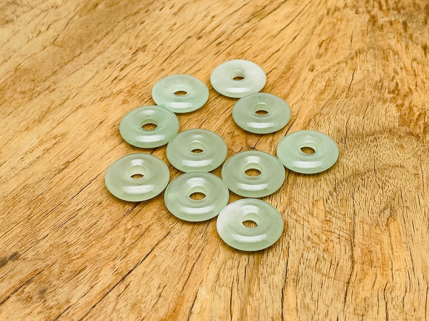 A 20mm aventurine crystal donut pendant with natural green gemstone, showcasing its polished, smooth, circular shape and vibrant color.