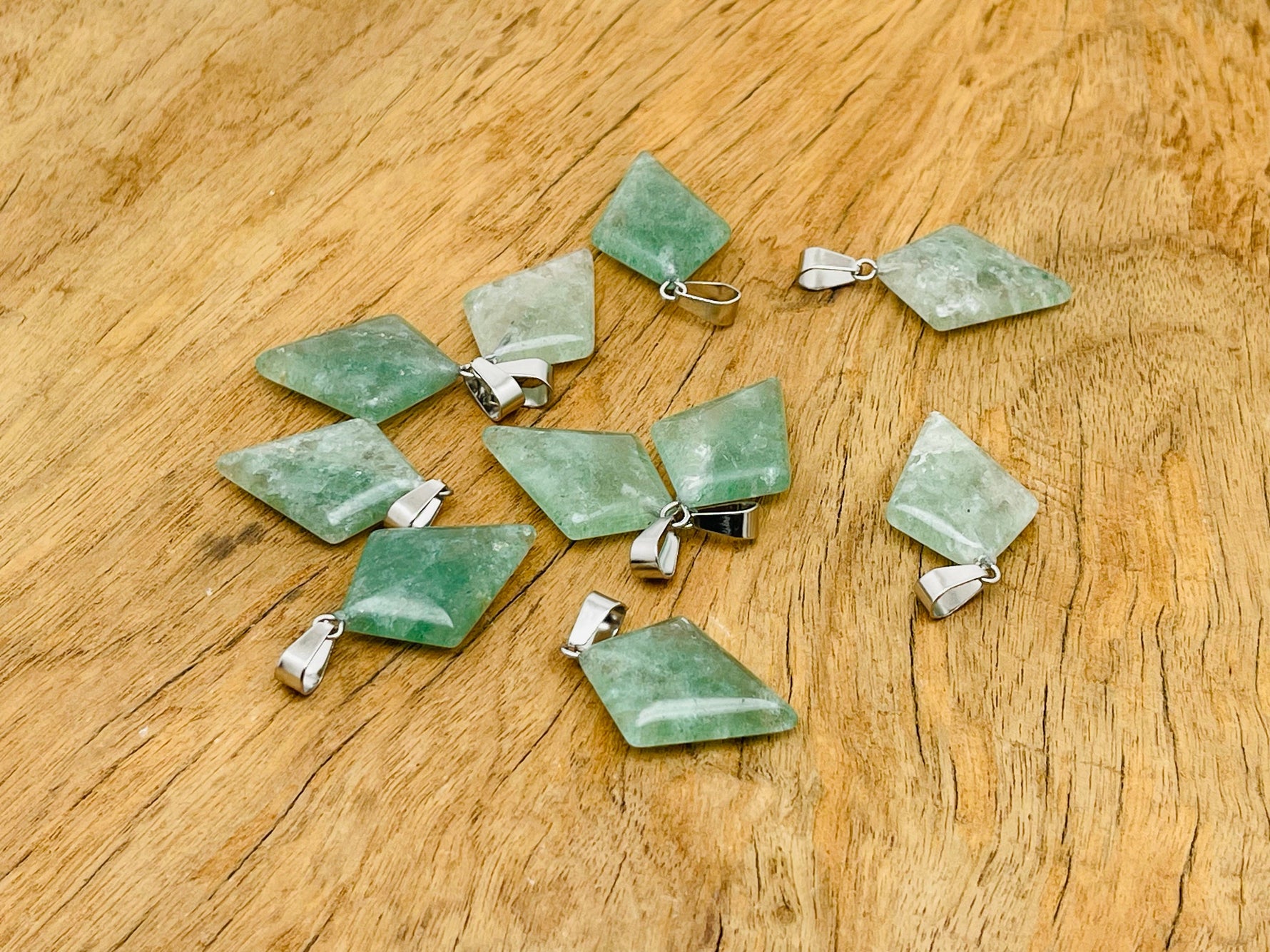 Green strawberry quartz triangle gemstone pendant with geometric design, showcasing vibrant green color and polished surface.