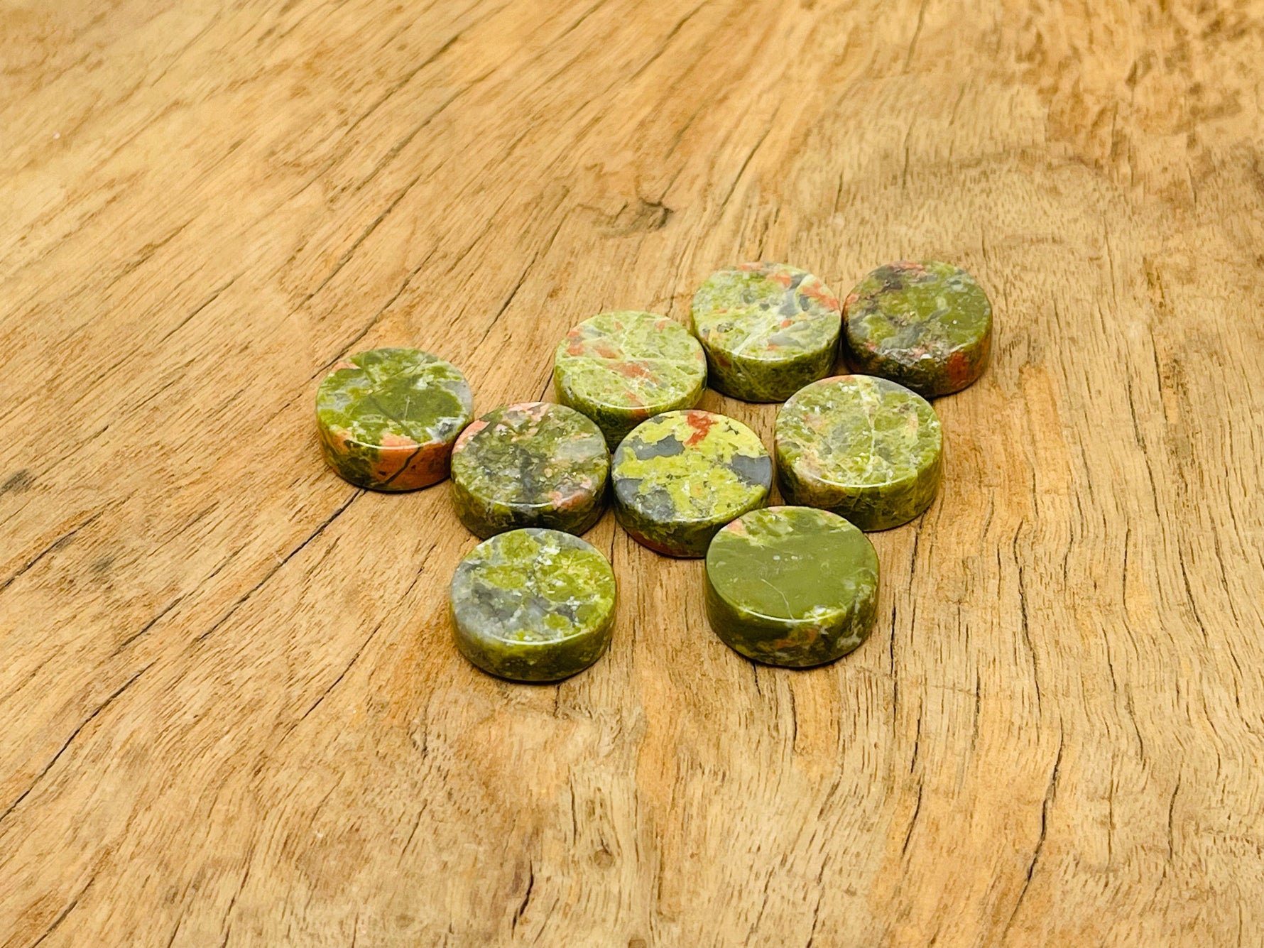 Round Unakite flat gemstone slab from GemstoneGO, showing green and pink mineral patterns on smooth polished surface.