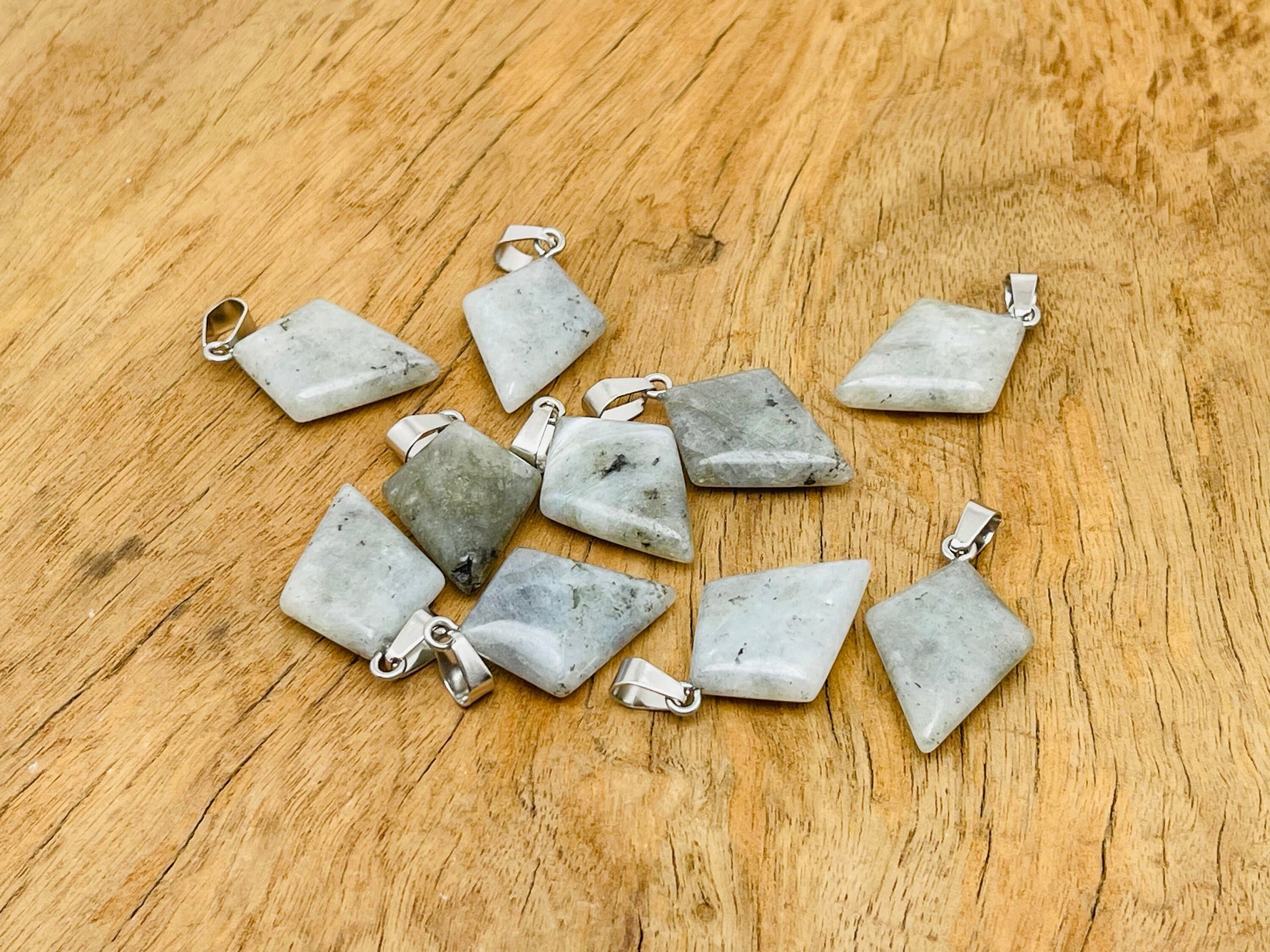 Labradorite triangle gemstone pendant with geometric design, showcasing iridescent colors and polished surface, by GemstoneGO.
