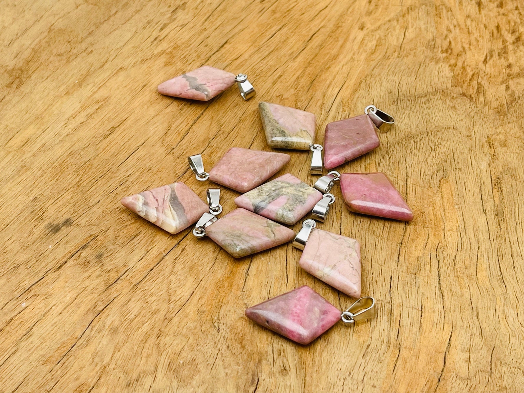 Rhodonite triangle gemstone pendant by GemstoneGO featuring a geometric design and polished finish, displayed against a neutral background.