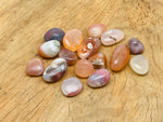 Crimson Agate tumbled gemstone from GemstoneGO showing smooth, polished red and orange hues with natural stone patterns.