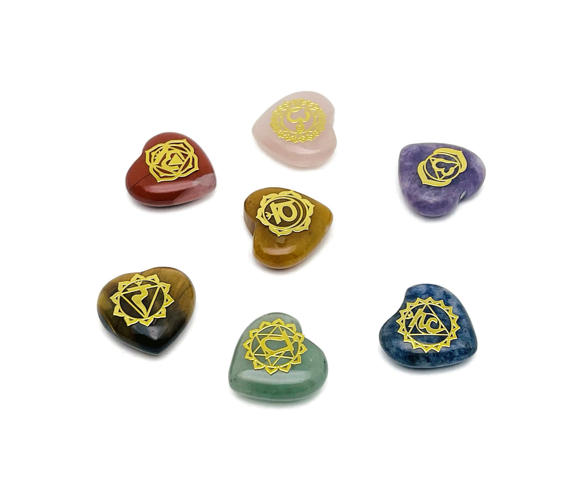 Set of seven heart-shaped chakra stones from GemstoneGO arranged in a meditation setting for crystal healing and energy balancing.