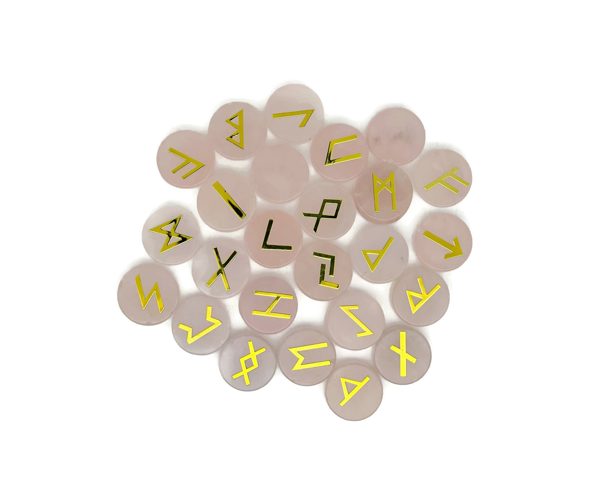 Set of 25 engraved rose quartz crystal rune stones with Elder Futhark alphabet from GemstoneGO, arranged in a crystal kit.