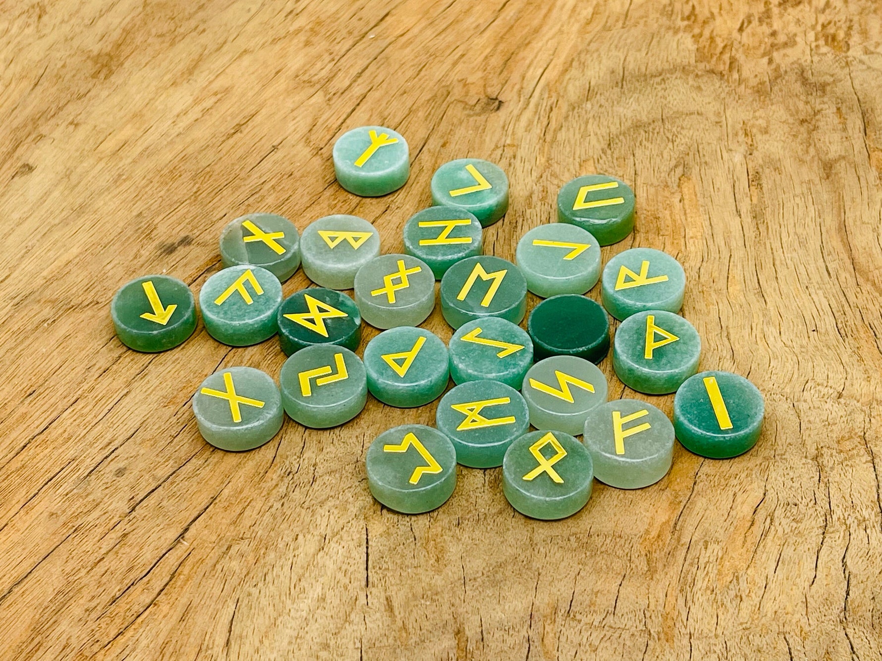 Set of 25 aventurine crystal rune stones engraved with Elder Futhark alphabet, part of GemstoneGO's crystal rune set.