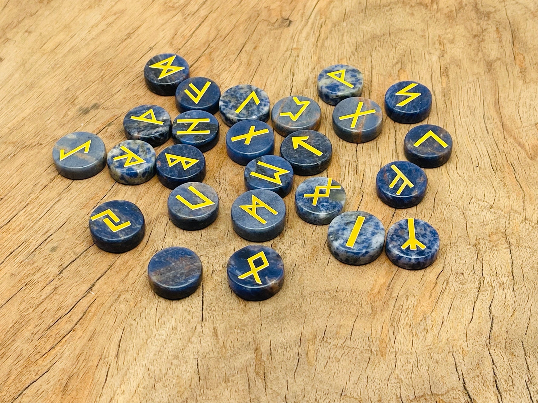 Set of 25 sodalite crystal rune stones engraved with Elder Futhark alphabet, arranged in a crystal kit for divination.
