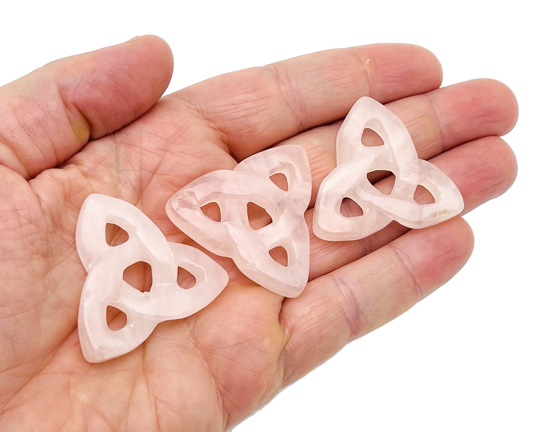 Rose quartz Celtic knot carved gemstone Trinity crystal by GemstoneGO, showcasing intricate knot design and smooth polished surface.