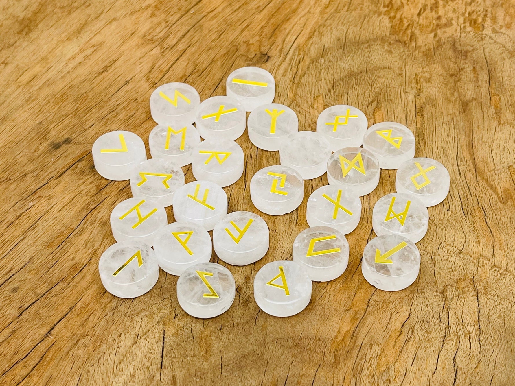Set of 25 clear quartz crystal rune stones engraved with Elder Futhark alphabet for divination and spiritual practice.