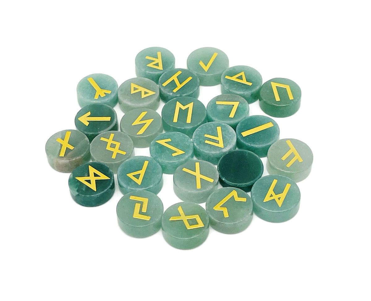 A set of 25 carved aventurine crystal rune stones with Elder Futhark alphabet engravings, arranged in a natural display.