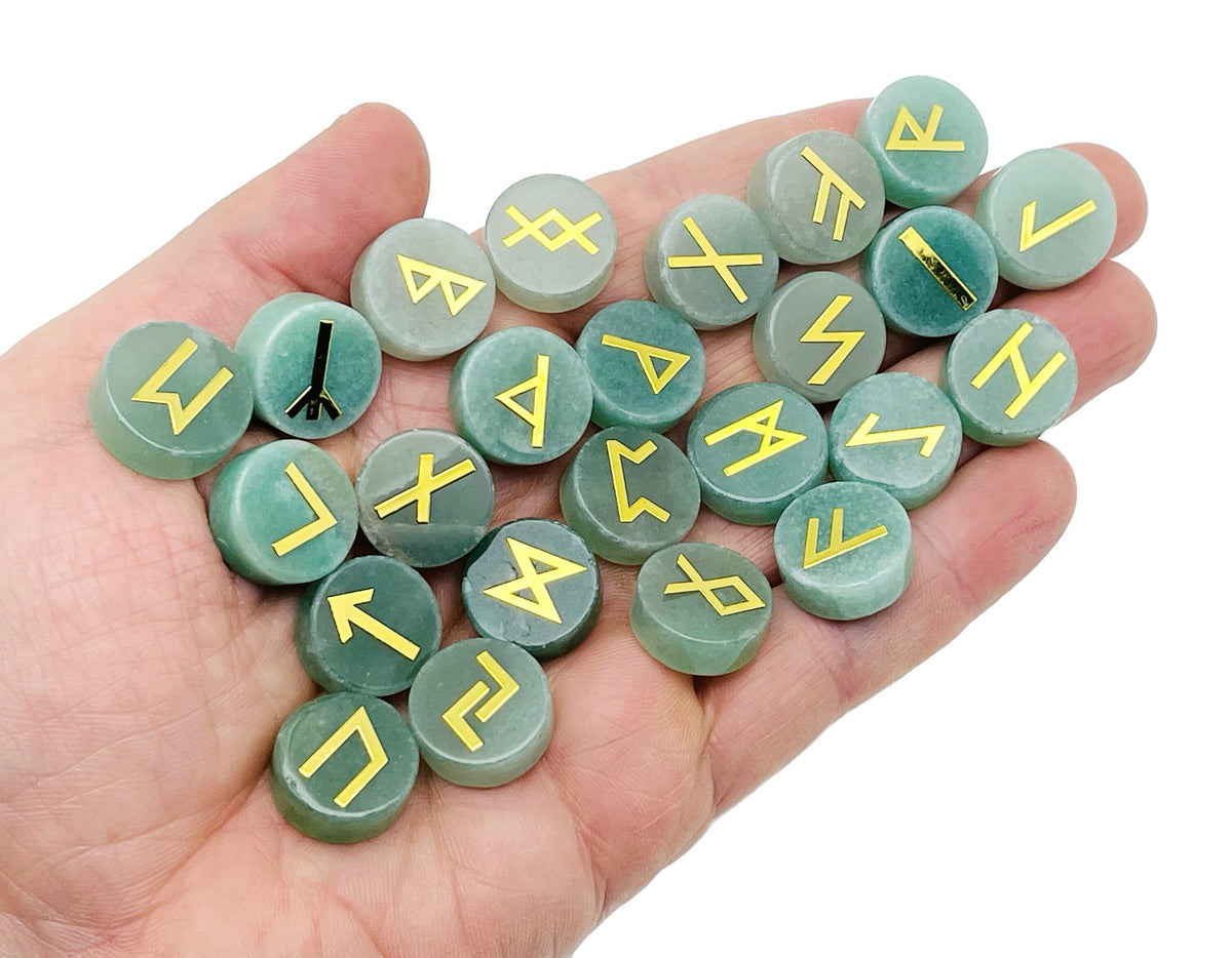 A set of 25 aventurine crystal rune stones engraved with Elder Futhark alphabet, arranged in a display.