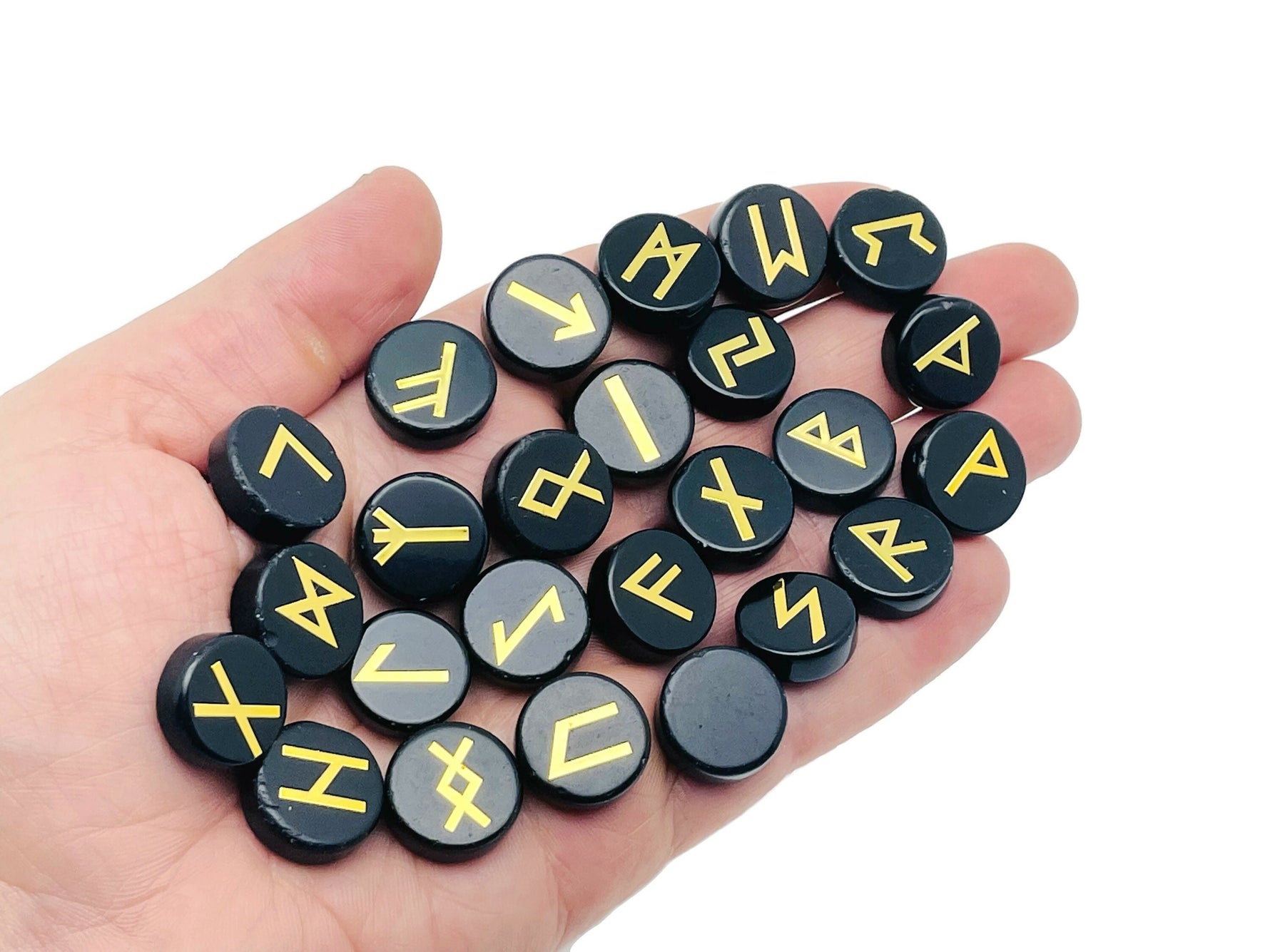 Set of 25 obsidian crystal rune stones engraved with Elder Futhark alphabet, arranged in a crystal kit for divination and rune reading.