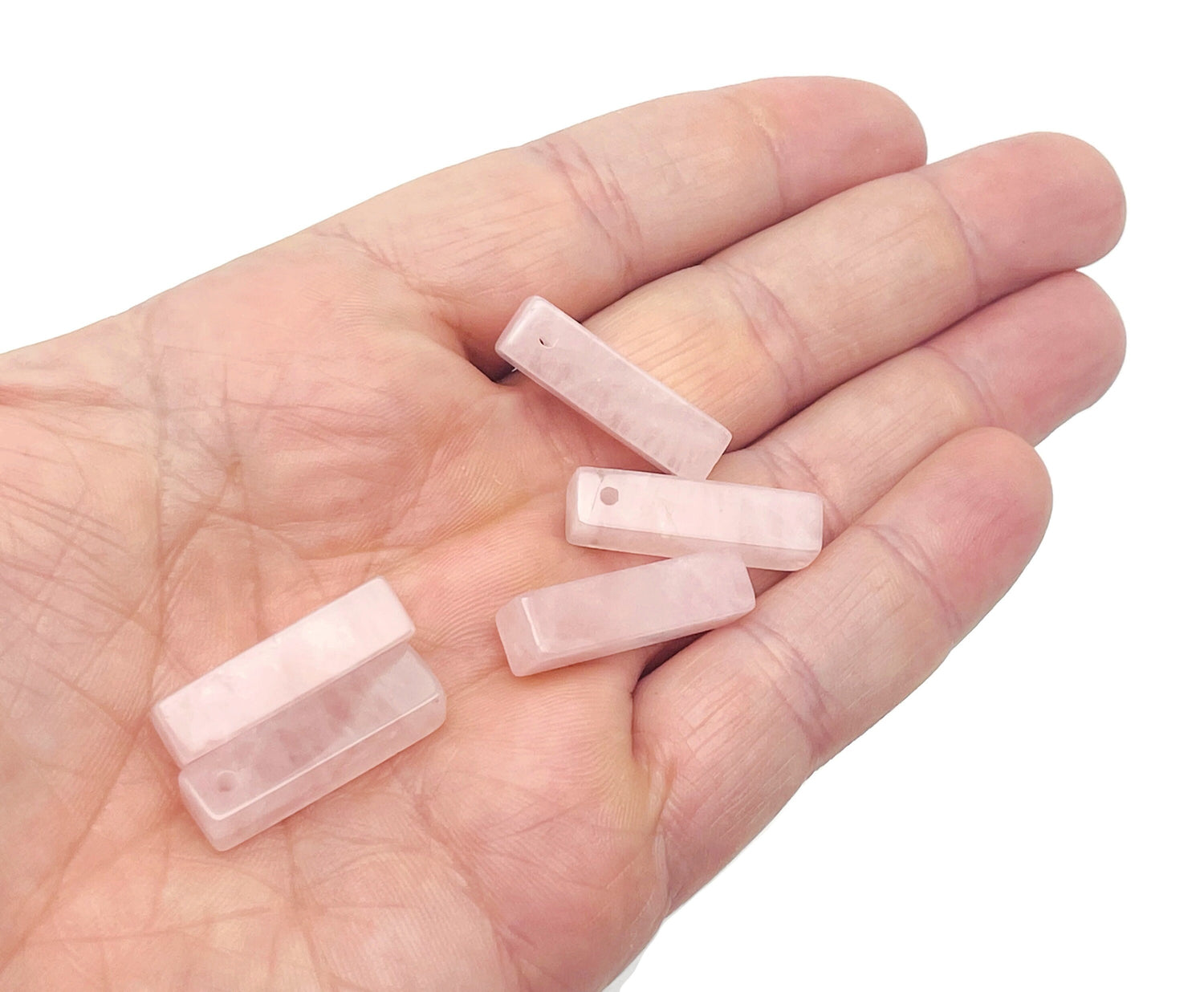 Rose quartz crystal pendant from GemstoneGO, drilled for jewelry making, showcasing a polished pink gemstone on a neutral background.