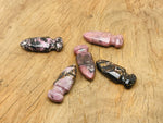 Carved Rhodonite sword dagger gemstone, 50mm, with detailed carvings, displayed against a neutral background.