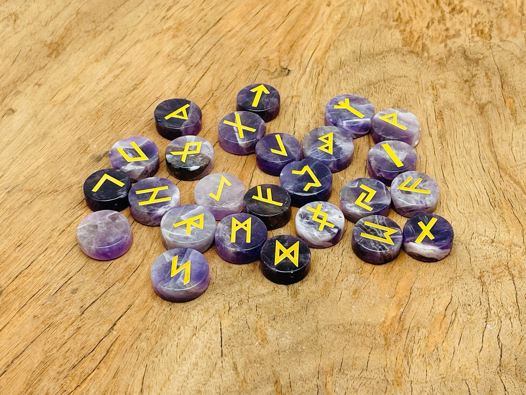 Set of 25 engraved amethyst crystal rune stones with Elder Futhark alphabet for divination and crystal healing.