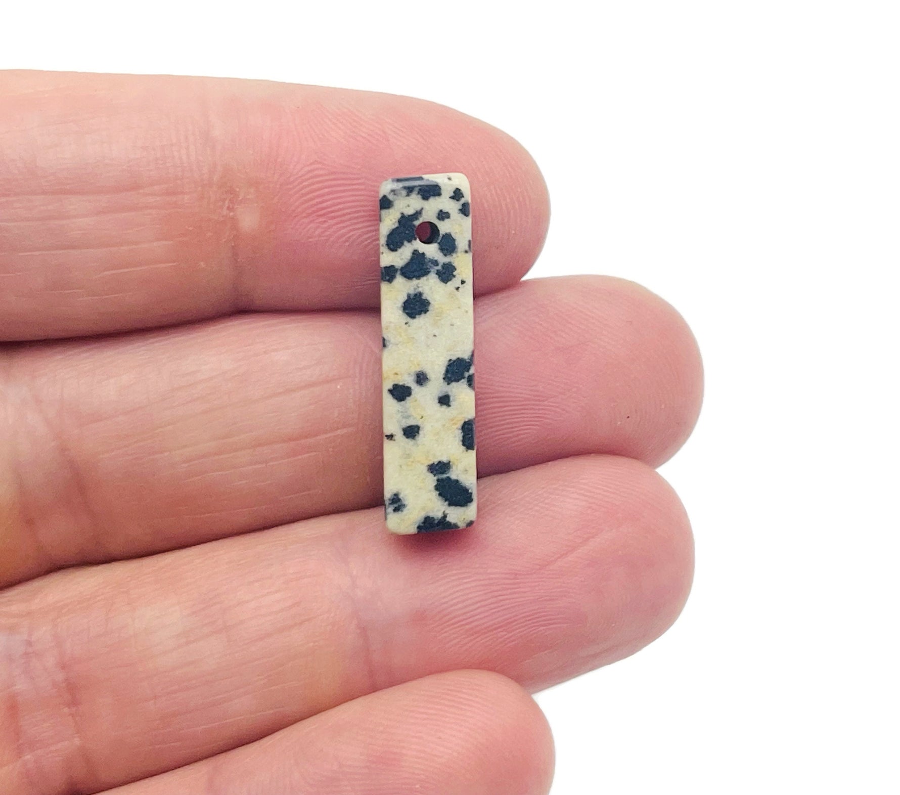 Dalmatian Jasper crystal pendant with drilled hole, natural stone for jewelry making, showcasing black spots on cream background.
