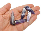 Polished amethyst bullet gemstone pendant with carved design, showcasing vibrant purple color and smooth, glossy surface.