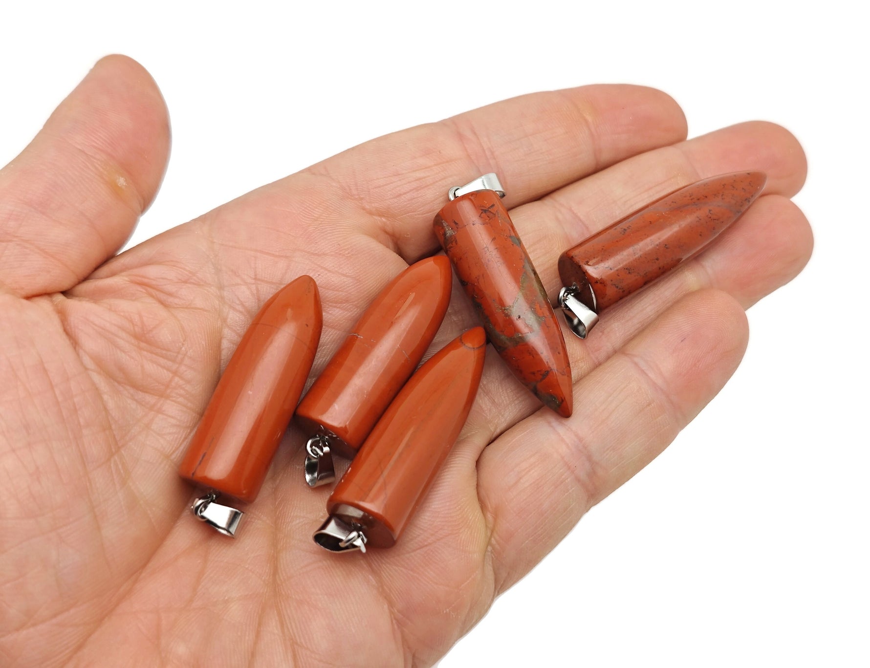 Polished red jasper bullet gemstone pendant with carved details, showcasing vibrant red color and smooth, rounded shape.