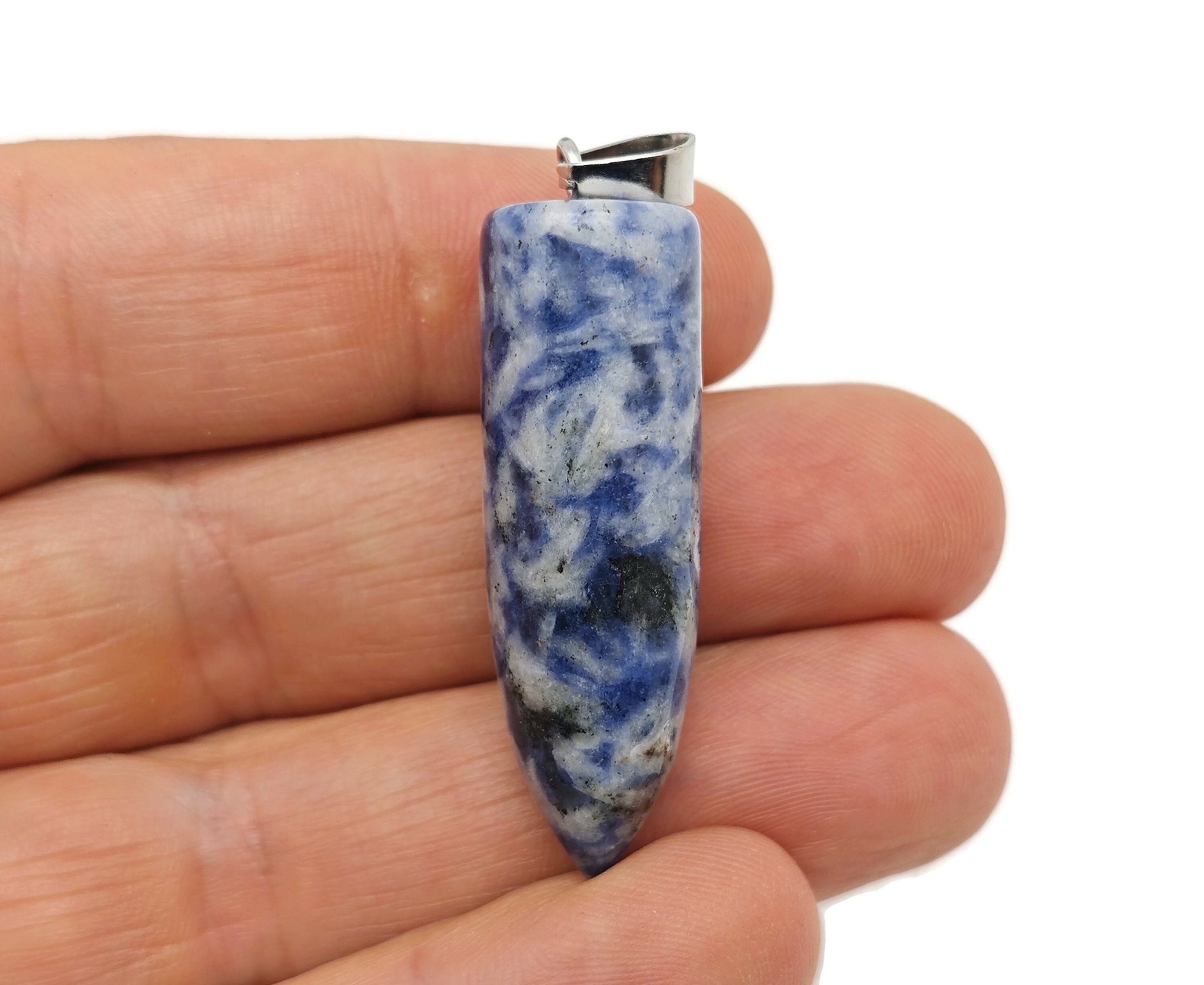 Polished blue spot jasper bullet gemstone pendant with carved details, featuring a smooth, rounded shape and natural stone patterns.
