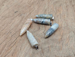 Polished Crazy Lace Agate bullet gemstone pendant with carved design, featuring vibrant, intricate patterns.
