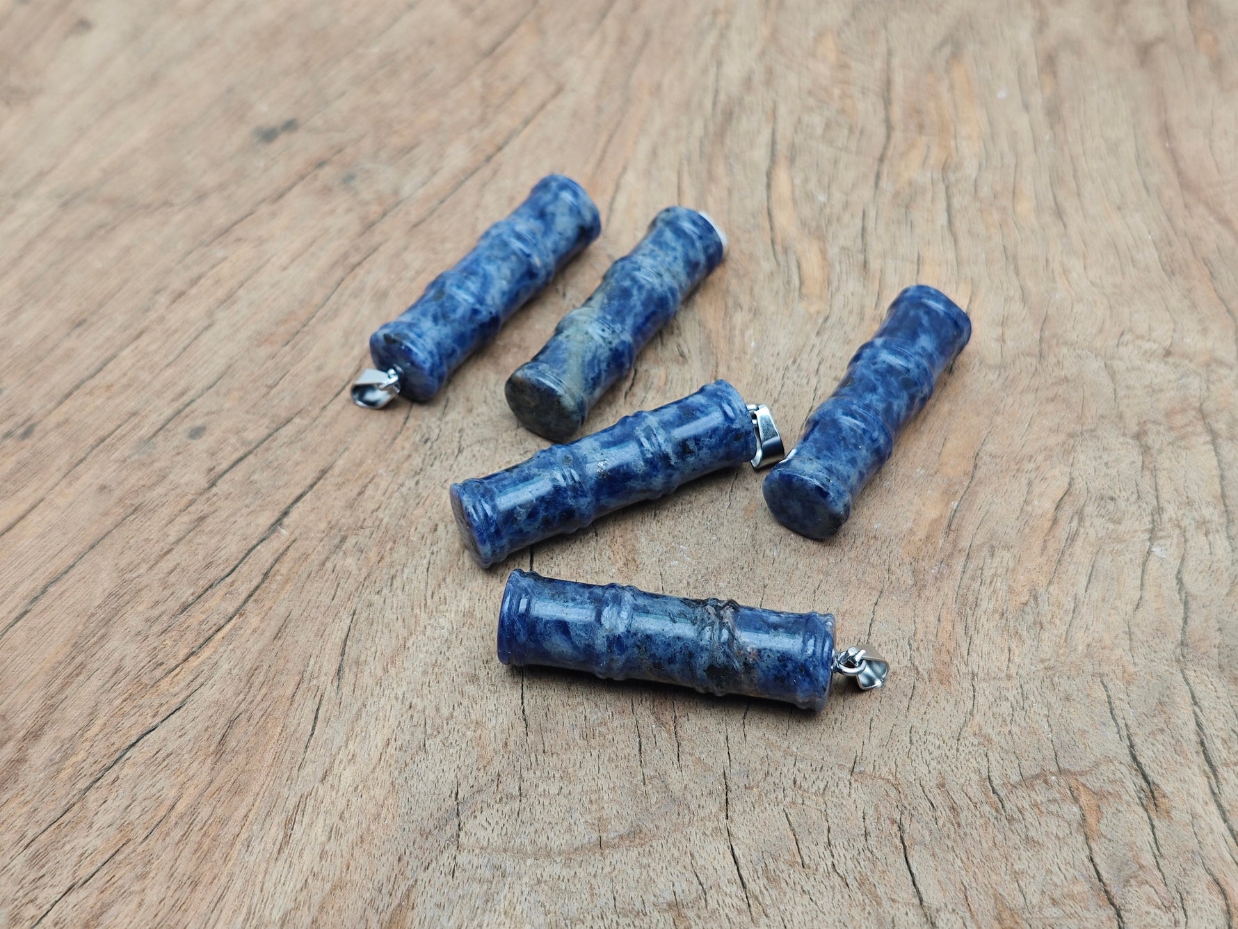 Sodalite bamboo-shaped crystal pendant with protective energy, featuring vibrant blue and white stone on a silver chain.