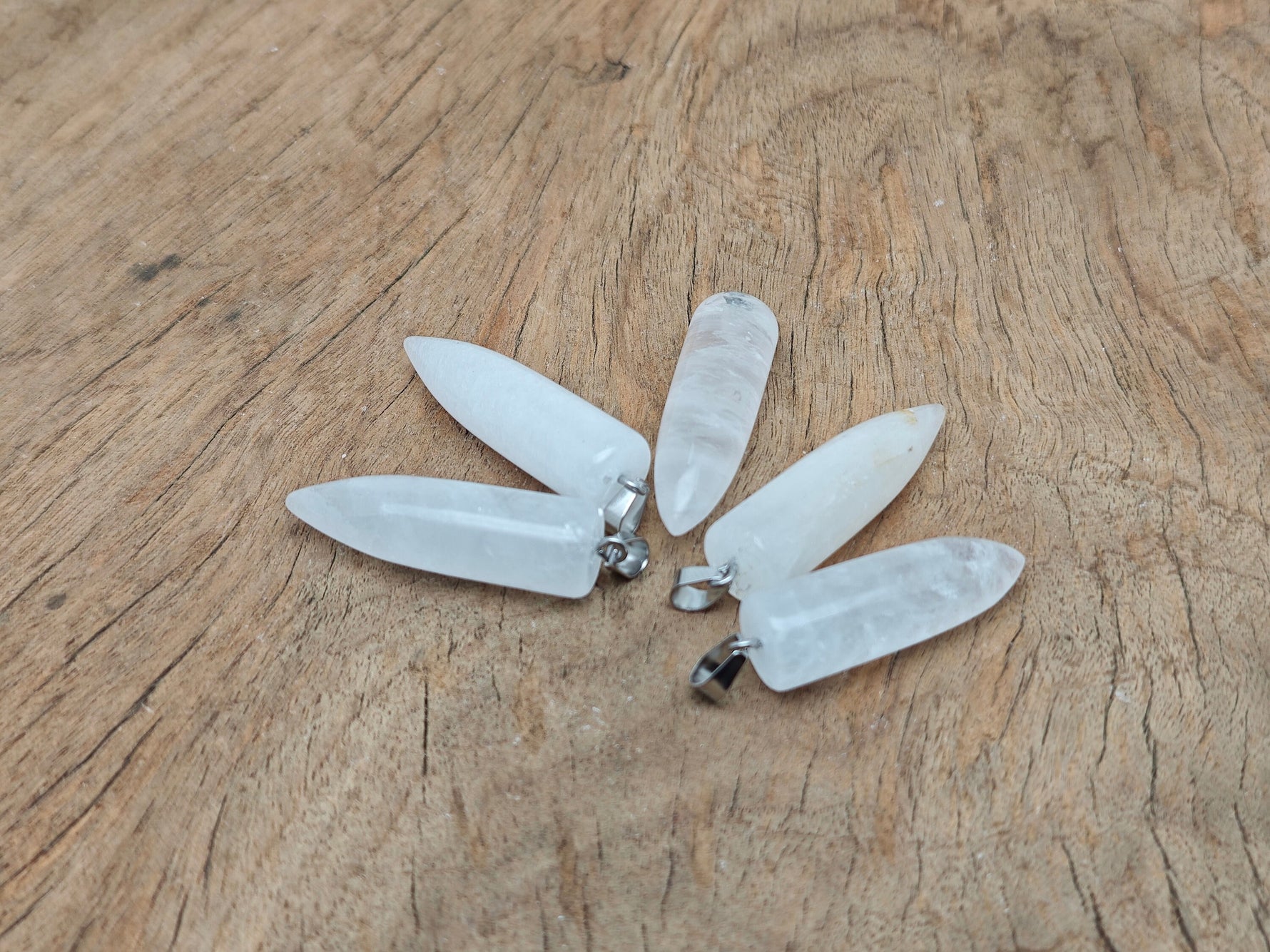 Polished clear quartz bullet gemstone pendant with carved details, showcasing a smooth, transparent crystal from GemstoneGO.