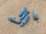 Polished blue spot jasper bullet gemstone pendant with carved details, featuring a natural gemstone shape and vibrant blue and brown patterns.