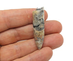 Polished Crazy Lace Agate bullet gemstone pendant with carved details, showcasing vibrant banding and natural stone texture.