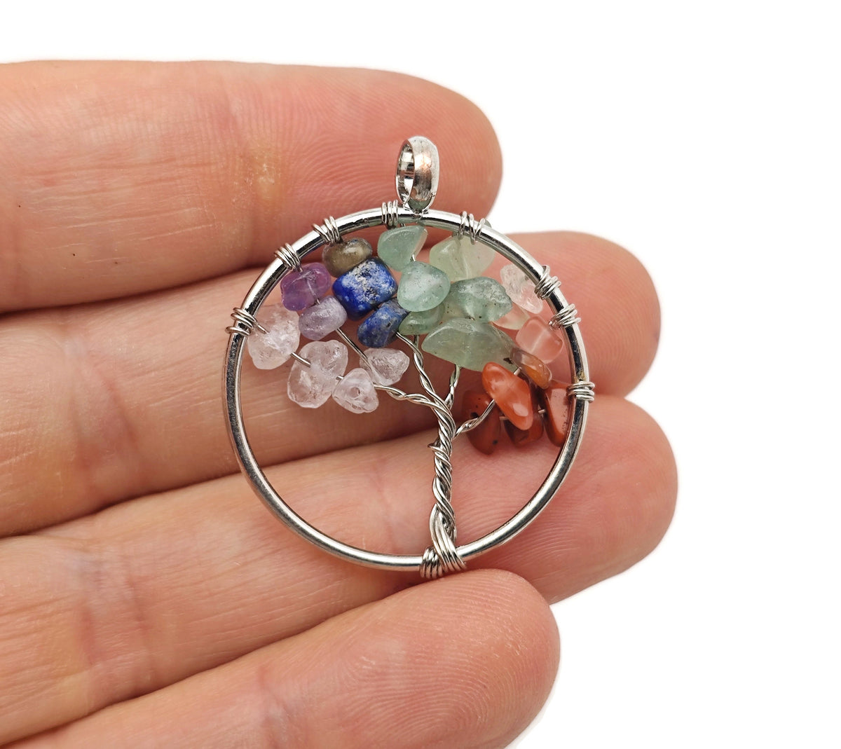 Seven Chakra Tree of Life gemstone pendant with colorful crystals on a silver setting, displayed against a neutral background.