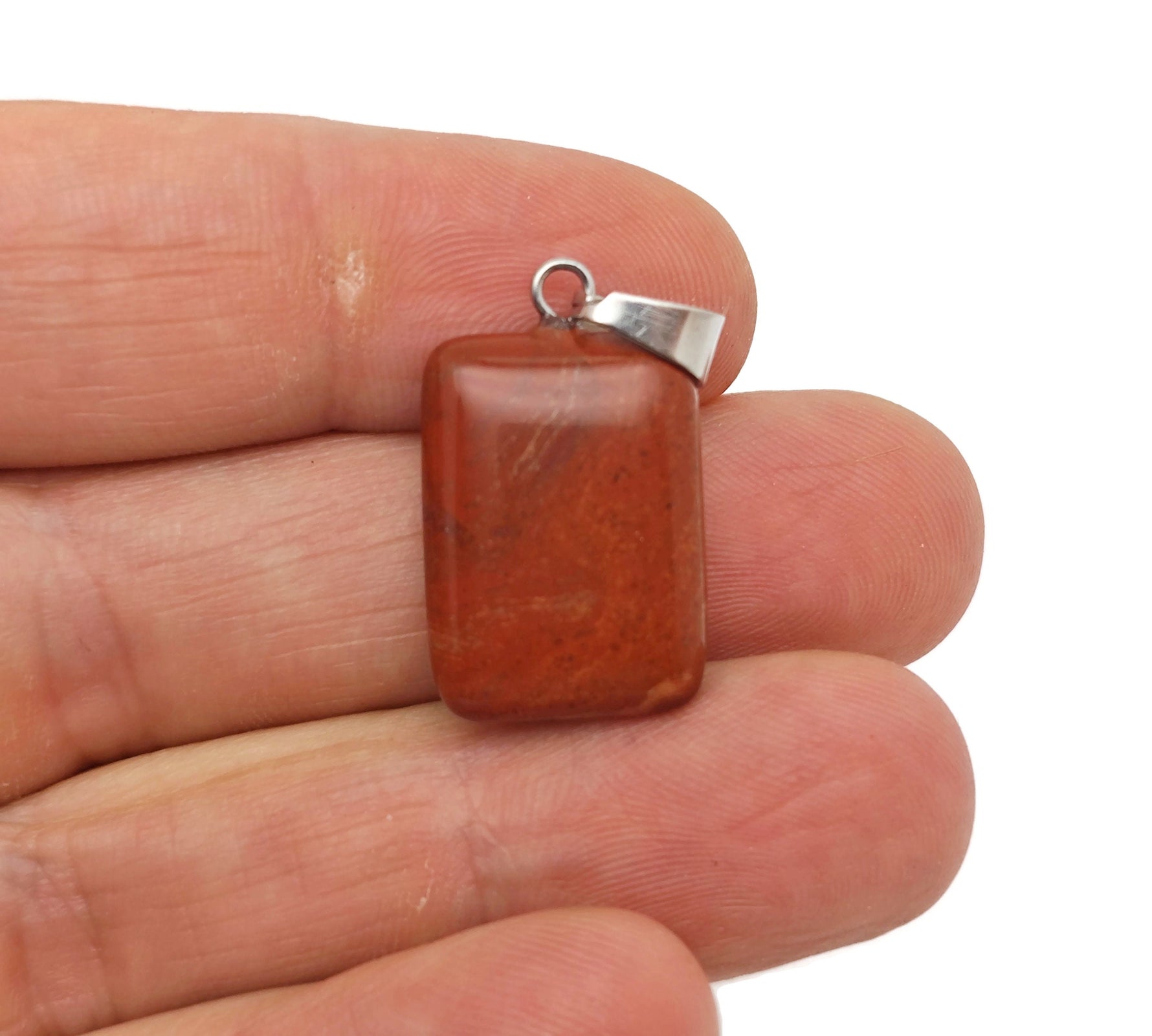 Red Jasper rectangle-shaped crystal pendant from GemstoneGO, showcasing vibrant red gemstone with polished, smooth surface.