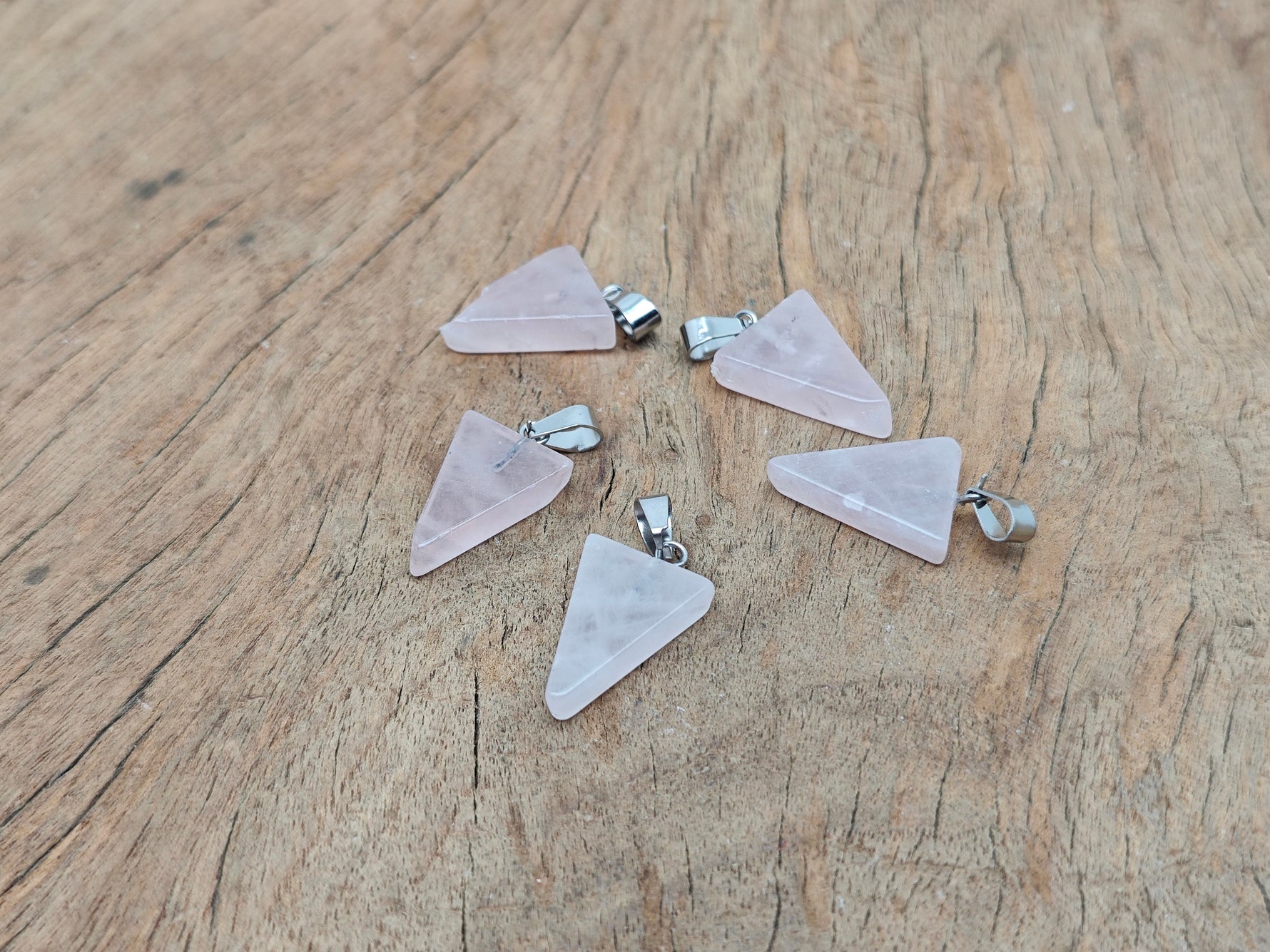 Rose quartz triangle crystal pendant from GemstoneGO, showcasing a smooth, polished pink gemstone in a triangle shape.