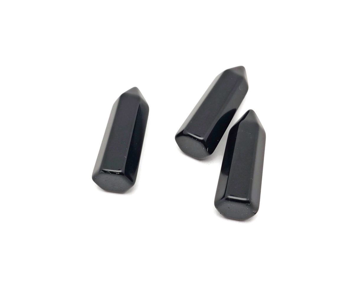 Polished 40mm black Obsidian Obelisk Tower crystal from GemstoneGO, showcasing its smooth, glossy surface and pointed shape.