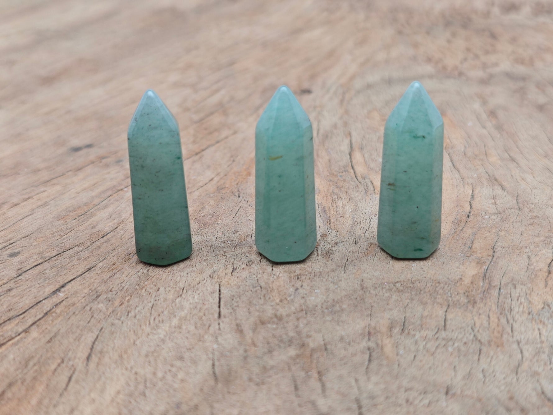 Aventurine obelisk tower crystal from GemstoneGO, 40mm tall, with green gemstone facets and pointed top on a white background.