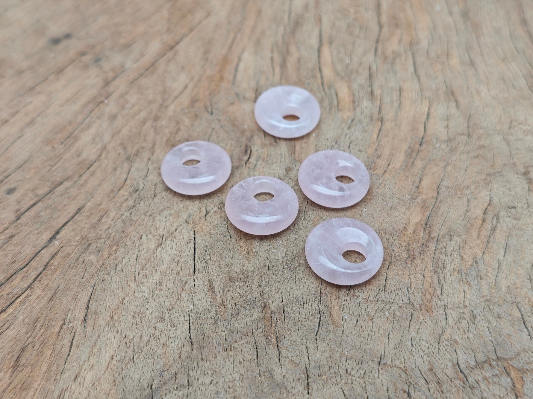 Rose Quartz crystal donut pendant featuring an 18mm Pi Stone from GemstoneGO, showcasing a polished pink gemstone with a smooth, rounded shape.