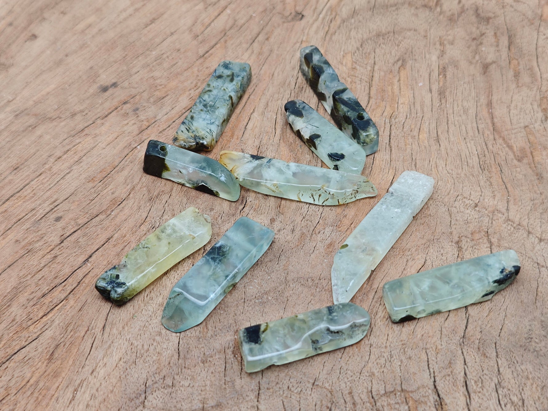 Prehnite drilled tumbled gemstone pendant from GemstoneGO, showing smooth green stone with drilled hole for necklace attachment.
