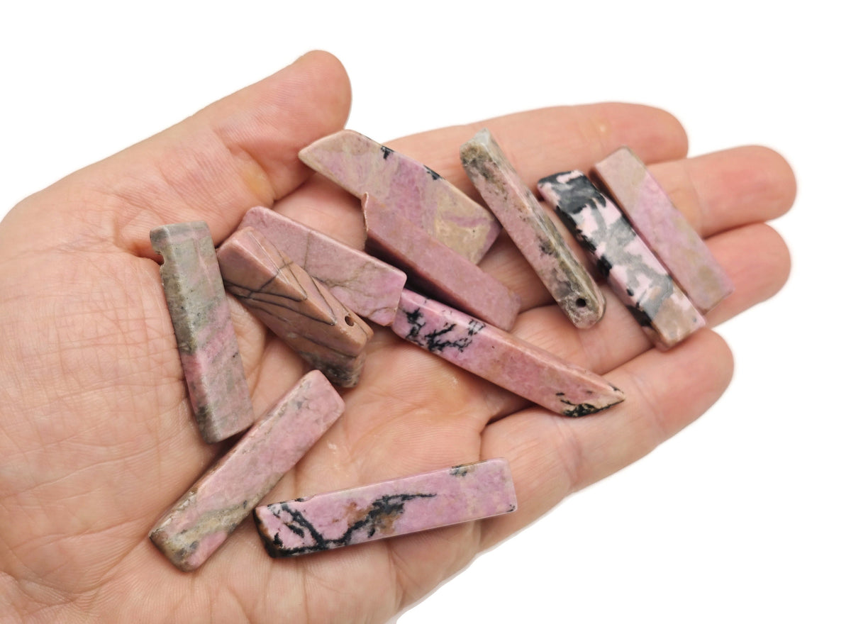Rhodonite drilled tumbled gemstone pendant from GemstoneGO, showcasing a polished pink and black stone with a drilled hole for jewelry.