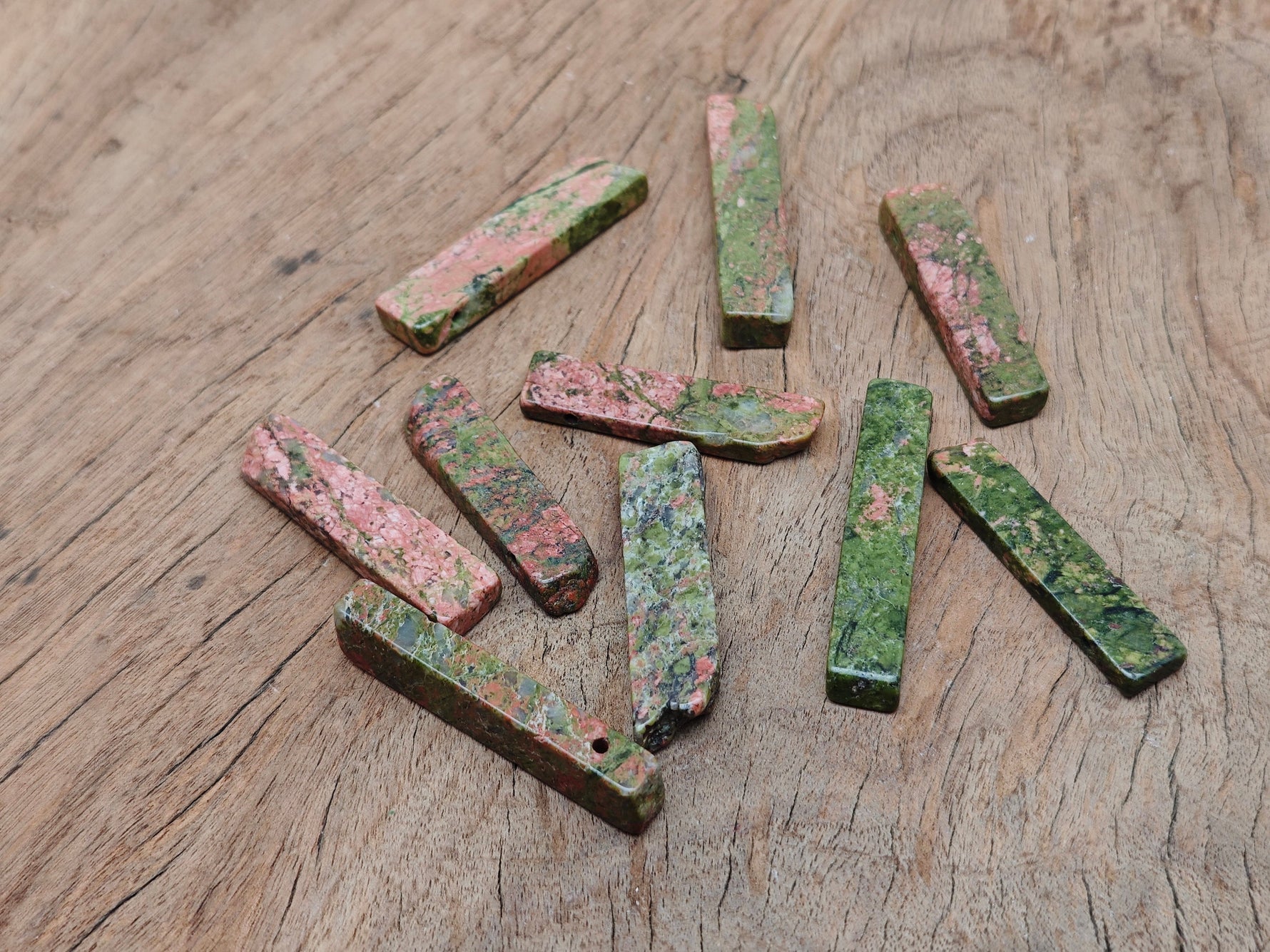 Unakite drilled tumbled gemstone pendant from GemstoneGO showcasing its vibrant green and pink natural stone pattern.